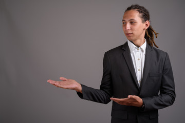 Young businessman with dreadlocks against gray background