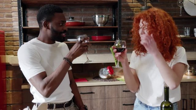 Couple Spending Time Together At Home In Modern Kitchen Curly Pretty Woman Drinks Red Wine And Handsome Afro American Man Enjoy The Talk Hanging Out Relationship Food Close Up Slow Motion