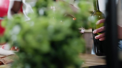 Close up hands people spend time together at home in modern kitchen woman drinks red wine and handsome afro American man cuts tomatoes enjoy the talk hanging out relationship food slow motion