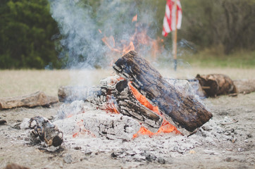 American flag behind campfire in the woods