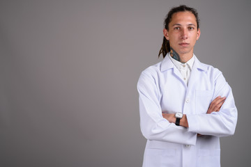 Young man doctor with dreadlocks against gray background