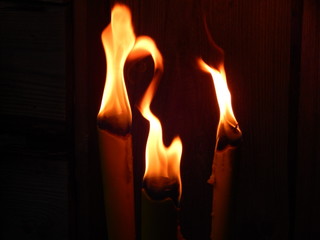 Leuchtende, tanzende Flammen dreier Gartenfackeln bei Nacht, Raum für Text