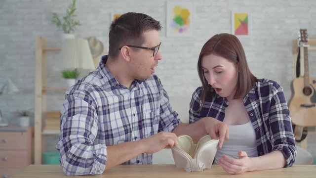 Shocked young couple looks into an empty wallet,the concept, the idea of lack of money