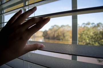 Hands opening up blinds in the day time