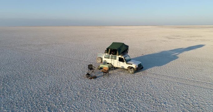 Zoom out high aerial view of tourists camping on the vast Makgadikgadi Pans, Botswana 