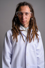 Young man doctor with dreadlocks wearing protective glasses agai