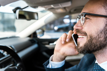 close up of happy bearded businessman talking on smartphone in car