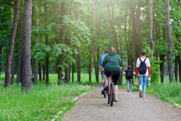 Group of very fat boy and girl friends  riding bikes in a forest. People riding bicycles in the green city park, active Healthy lifestyle . Close up. 