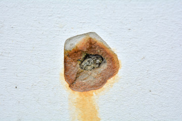 White concrete wall with rusted hole