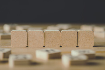 selective focus of five blank cubes surrounded by blocks with letters on wooden surface isolated on black