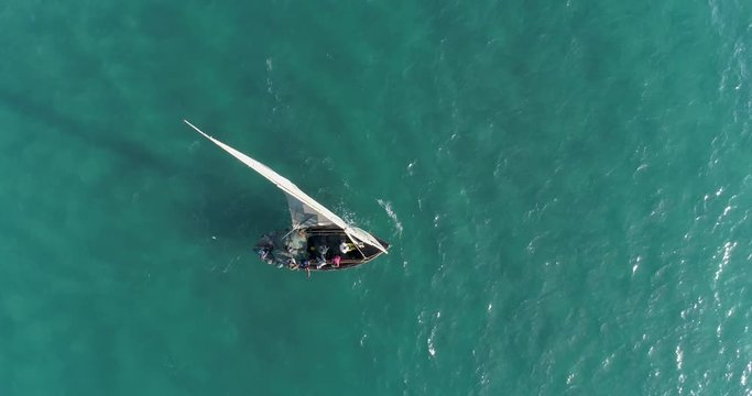 Straight own aerial view of fisherman on a traditional dhow fishing boat heading out to sea for the days fishing
