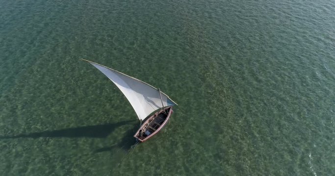 Straight down aerial view of a lone fisherman on a traditional dhow fishing boat heading out to sea for the days fishing