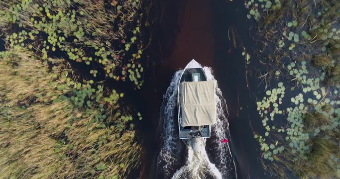 High aerial zoom out view of a tourist boat making its way down one of the many curving waterways of the Okavango Delta