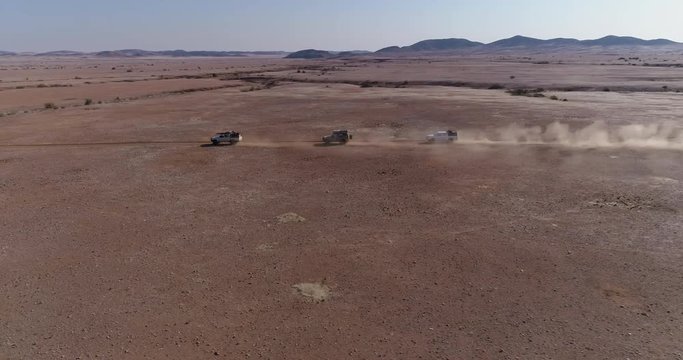 4K zoom in aerial view of 4x4 vehicles driving through the Namib desert, Namibia