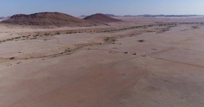 4K aerial view of 4x4 vehicles driving through the Namib desert, Namibia
