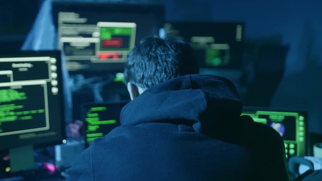 Concentrated skillful hacker working on code stealing information in the smoky room at night.
