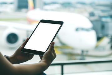 Mockup image of a woman's hands holding and using black tablet pc with blank white screen while...