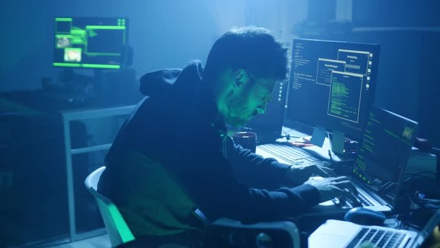 Back view of professional hacker at work. Close-up of smart man working with codes to steal important data in the office.