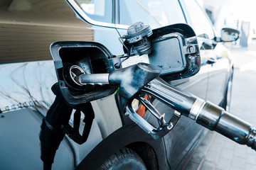 Selective focus of black modern automobile refueling with benzine on gas station