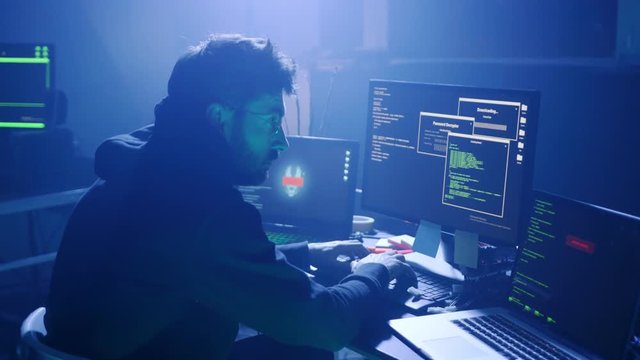 Profile of concentrated man typing data code on laptop keyboard at the workplace. Tired developer working late in software development company.