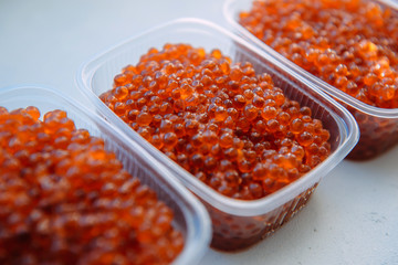 Salmon caviar close-up. Plastic containers with red caviar isolated on white background. Sea delicacy, fresh catch.