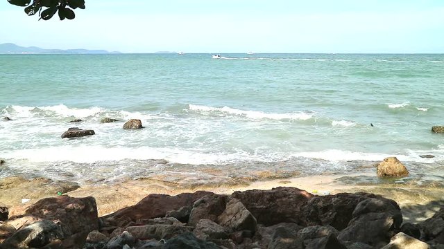 wave attact stone near beach speed boat on sea silhouette tree