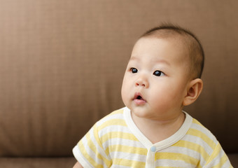 portrait of little small asian baby infant sitting and looking to the left side