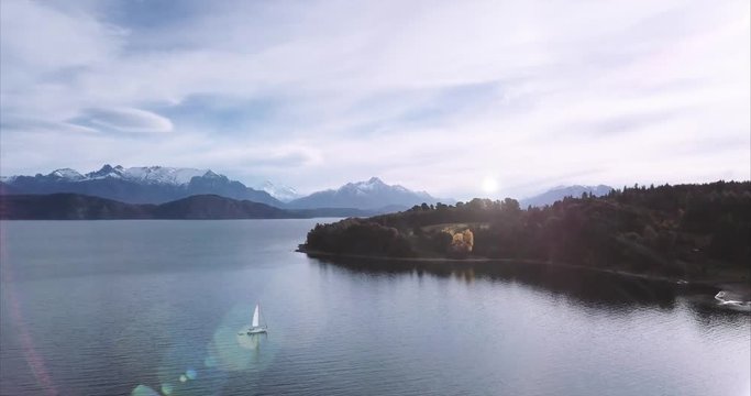 Aerial view of a Hispanic woman relaxing on the bow of the sailboat looking at the beautiful Patagonian lake Nahuel Huapi. 4k