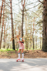 full length view of blonde girl in knee socks skateboarding on road