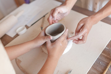 Two pairs of hands make a Cup of clay