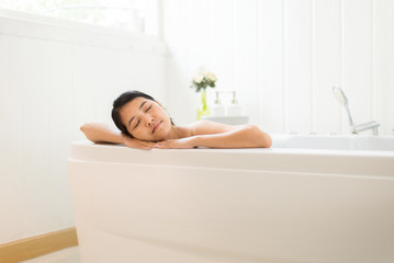 Obraz na płótnie Canvas Beautiful asian woman close eye and relax on jacuzzi bathtub in the morning,Female lying body in water at hotel,Copy space for text