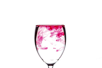 Red food coloring diffuse in water inside wine glass