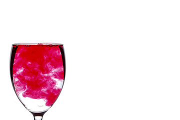 Red food coloring diffuse in water inside wine glass