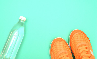Sporty shoes and bottle on pink background.