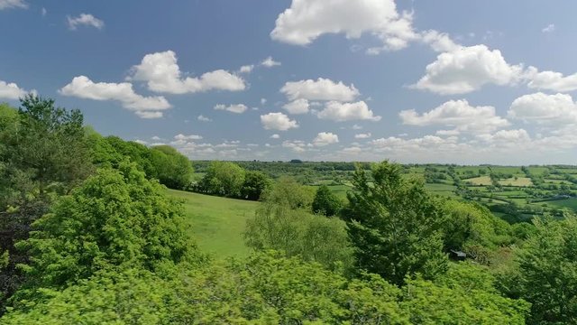 English fields and green springtime treetops. In the background a swathe of farming land. Amazing blue sky