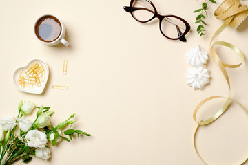 Fototapeta na wymiar Flat lay women home office desk with coffee cup, glasses, roses flowers bouquet, paper clip, ribbon and feminine golden fashion accessories. Top view female workspace, beauty blogger girls desktop.