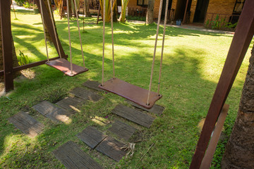 Wooden swing hanging in a beautiful garden near the bungalow. The inner territory of a beautiful hotel on the seafront. Small houses on the resort in Asia.