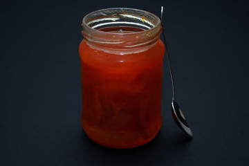 Glass jar of jam on a dark background