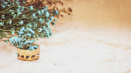 Macro small white flowers in a small bamboo woven basket on a linen fabric background