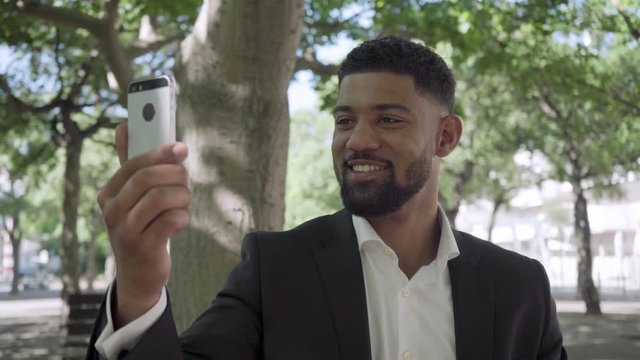 Handsome bearded African American man having video call. Smiling young businessman talking to smartphone. Communication and technology concept