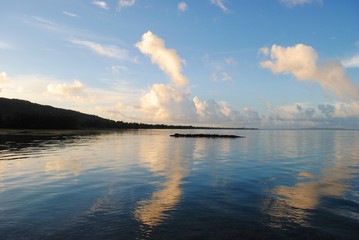 Clouds in the skies reflected in the waters of the ocean at sunset