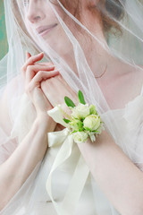 Bride wearing wrist corsage made of rose and eustoma flowers.