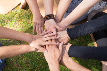 Top view of stack of hands against green grass. Friendship, teamwork or community gesture. Unity or team concept