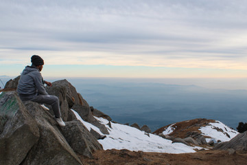 A young trekker looking at the Himalayan landscape. Location: Triund, Himachal Pradesh, India.