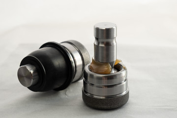 two tie-rod ends, or a ball joint, on one the dust cover is visually removed and lubrication is visible, the automobile part