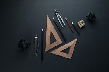 Drawing board flat lay with pencils, compasses, rulers, crumpled paper balls. Dark header for...