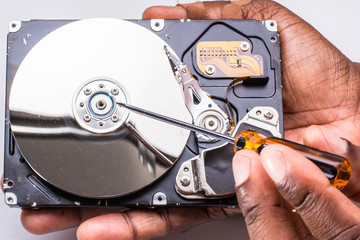 Male technician hand holding and working on dusty computer hard drive with scewdriver