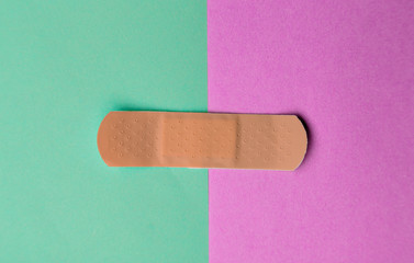 Adhesive bandage or Sticking plaster on a two colored paper background.