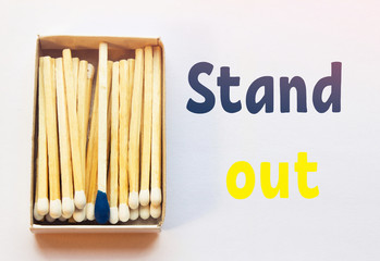 White matches and one match of blue color in a box. Difference, self respect and acceptance concept. Motivational phrase on the image. Opposition, uniqueness, individualism concept. Not alike.