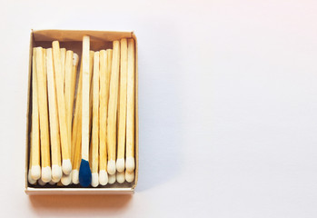 White matches and one match of blue color in a box. Self respect and yourself acceptance concept. Copyspace on the right side of the image for designers. Uniqueness and black sheep concept.